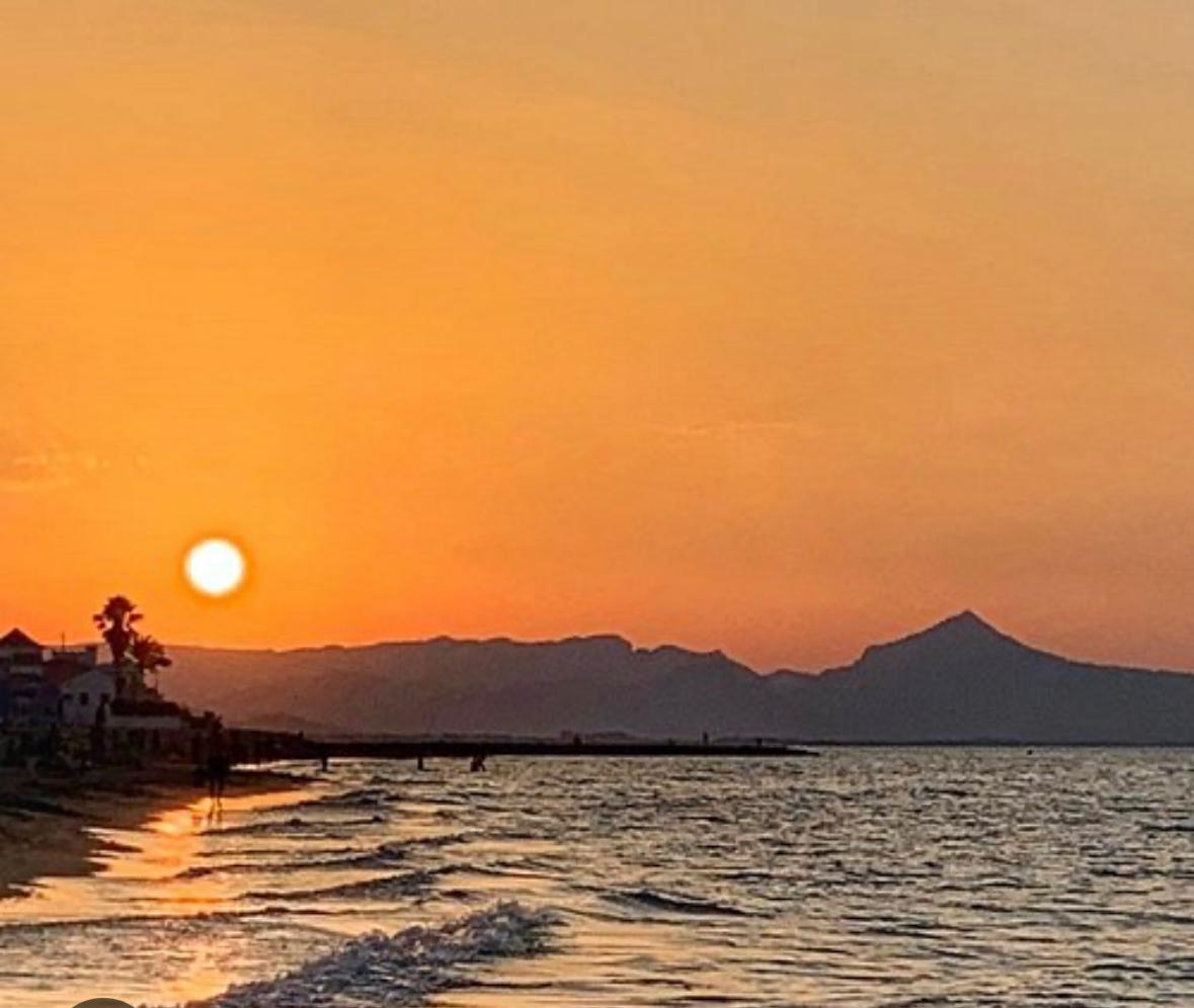 Zonsondergang boven zee met bergen aan de horizon
